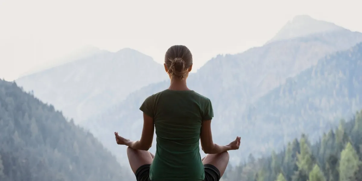 fit girl meditating, doing relaxation exercises with mountains at background meditation, healthy lifestyle, self care, yoga, leisure concept