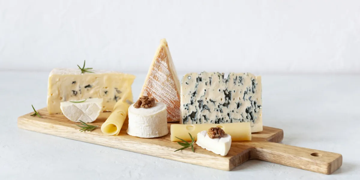 different types of cheese on a cutting board on white background
