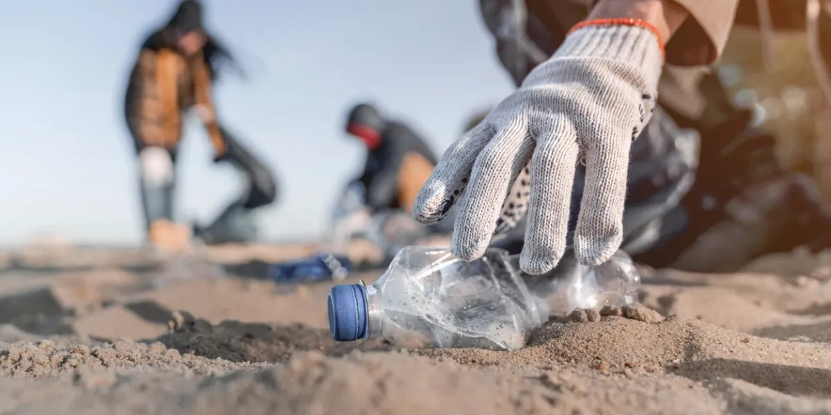 volunteer man collecting trash on the beach ecology concept