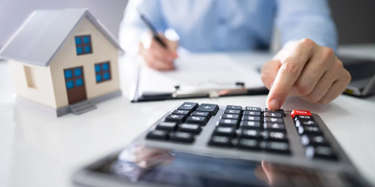 close-up of a person hand calculating a real estate property tax on wooden desk