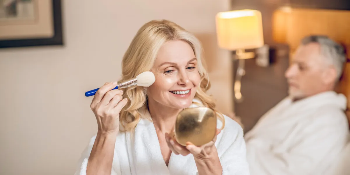a happy woman cute blonde woman doing make up and looking happy