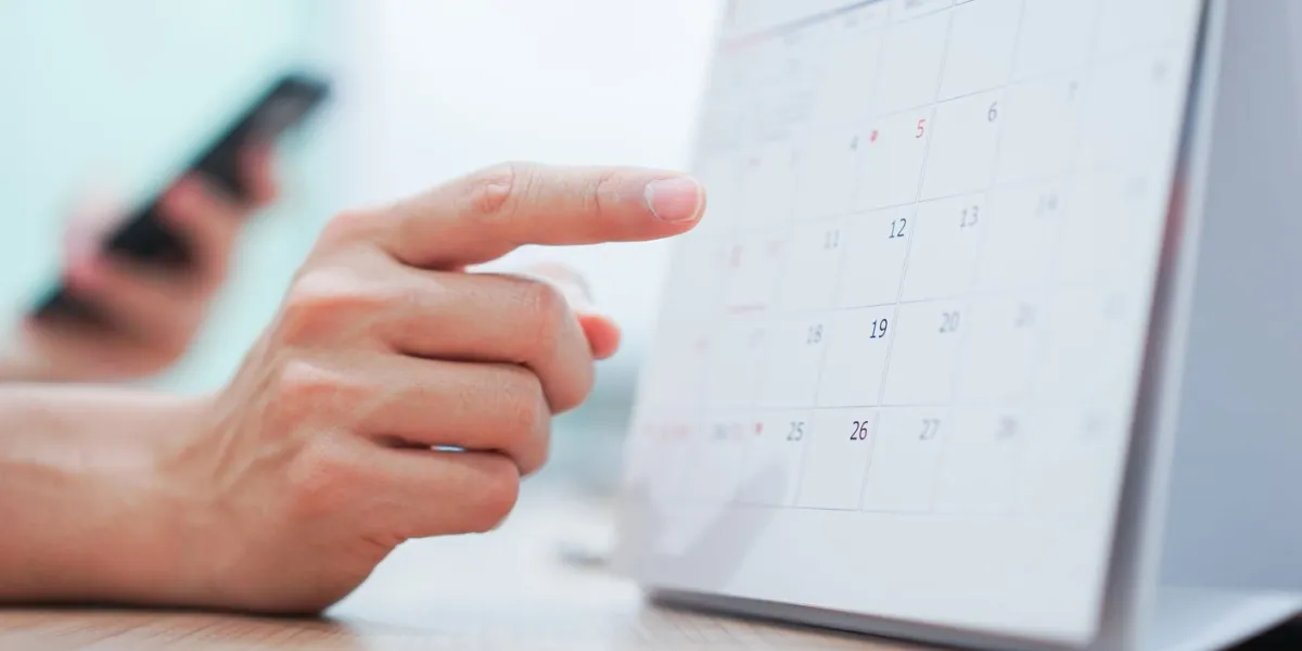 close up on employee man hand using finger pointing schedule (timetable) on calendar to make appointment meeting or manage timetable each day , life balance concept