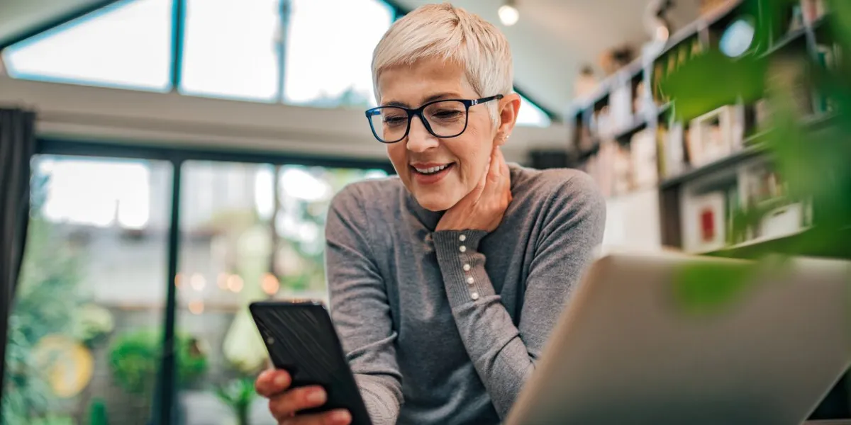 portrait of a cheerful senior businesswoman using smart phone at home office, close-up