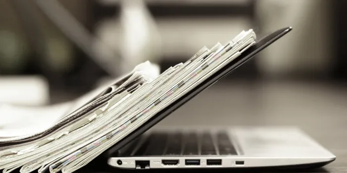 open laptop and stack of newspapers daily journals with news and personal computer concept for different sources of information - digital device screen or paper pages