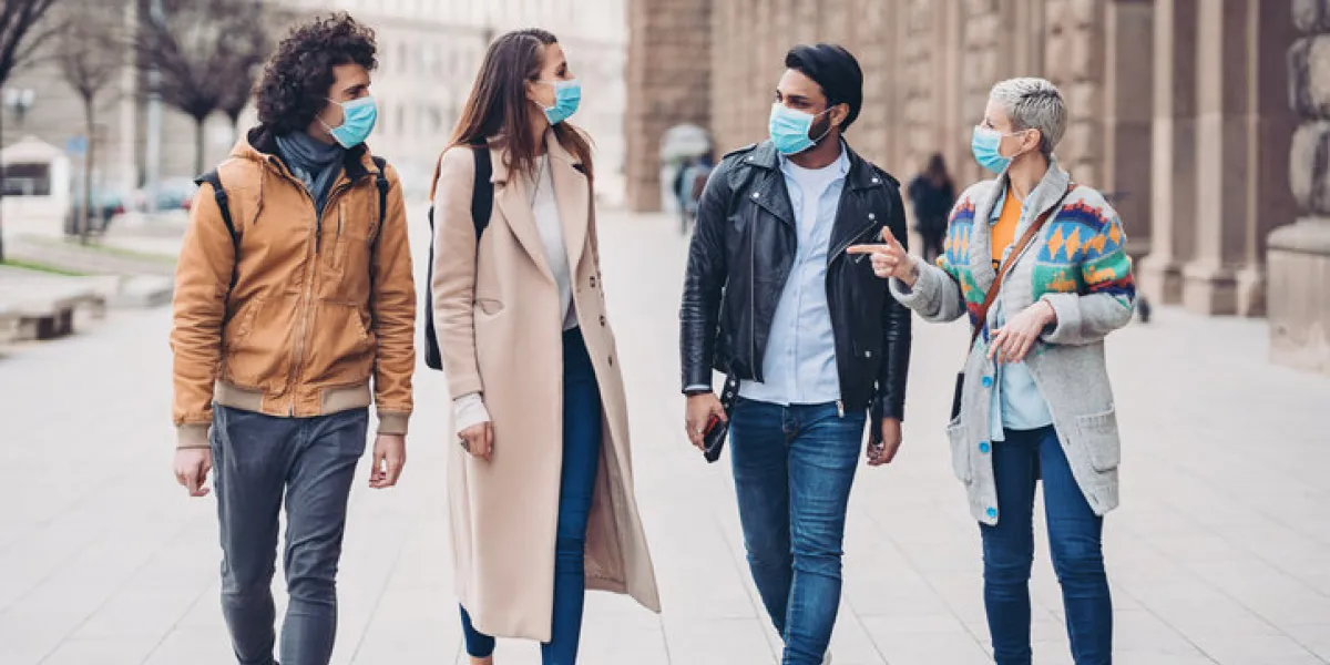 group of people with protective masks walking outdoors in the city