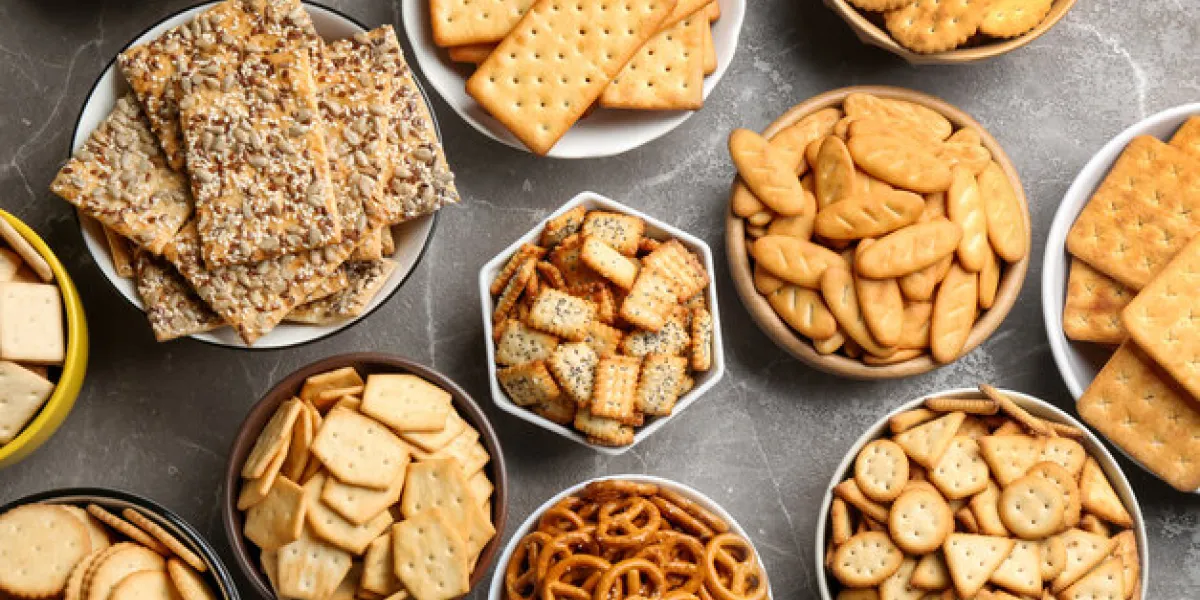 different delicious crackers in bowls on grey table, flat lay