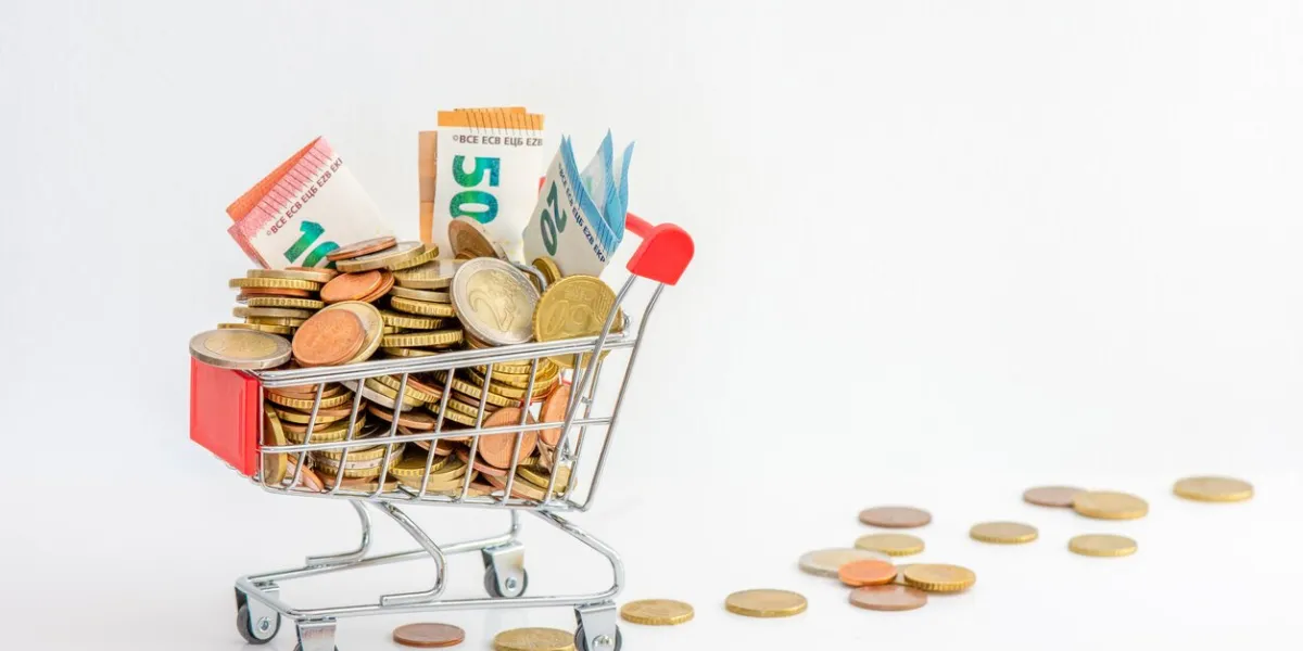europe  shopping cart overflowing with cash (euro coins and banknotes) concepts of rising prices, purchasing power and growing inflation in the euro zone white background