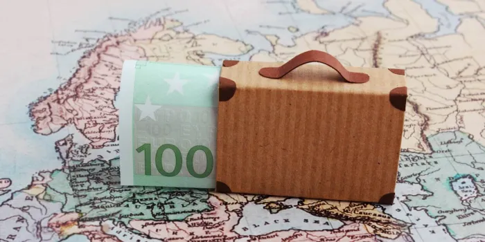 europe city trip travel budget concept with 100 euro note and suitcase on map