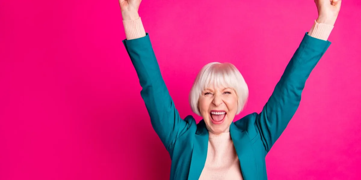 portrait of her she nice attractive cheerful cheery overjoyed gray-haired lady wearing, blue green jacket rejoicing rising hands up isolated on bright vivid shine vibrant pink fuchsia color background