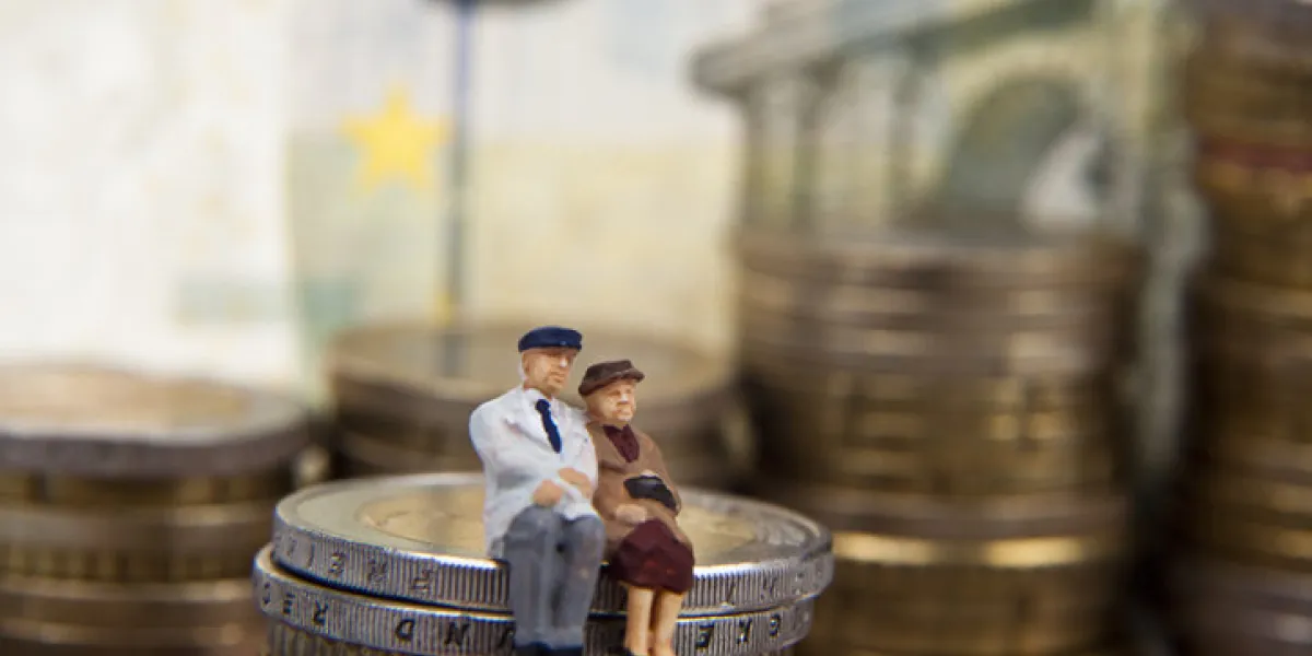 elderly couple figurine placed on stacks of coins