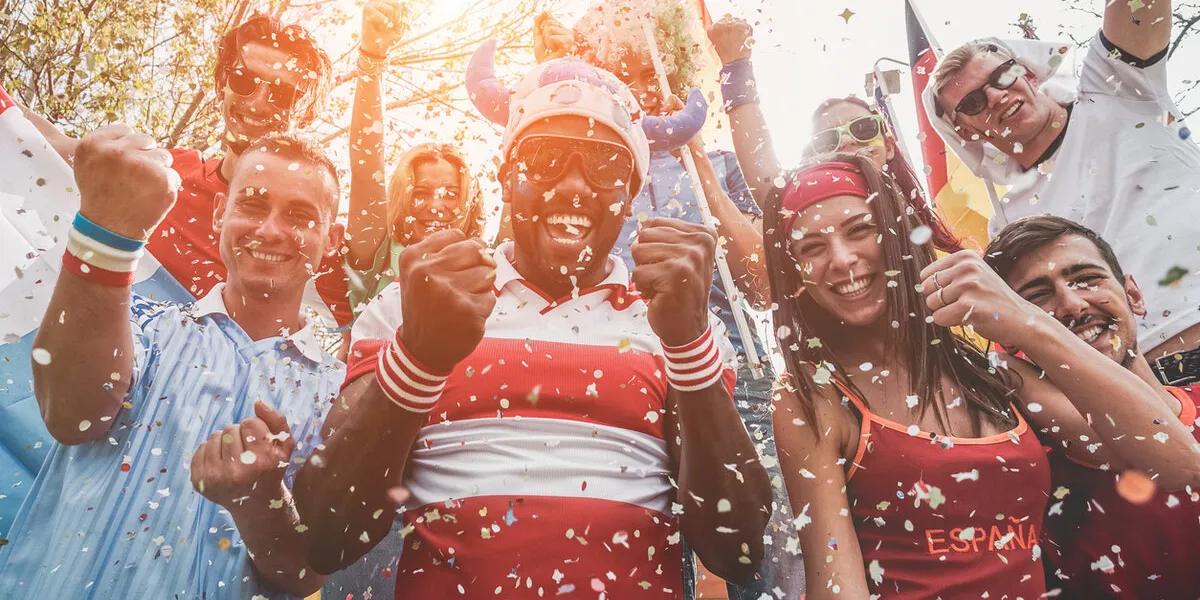 multinational football supporters celebrating the begin of world competition - happy multiracial people having fun together outside of stadium - main focus on black man - sport and bonding concept