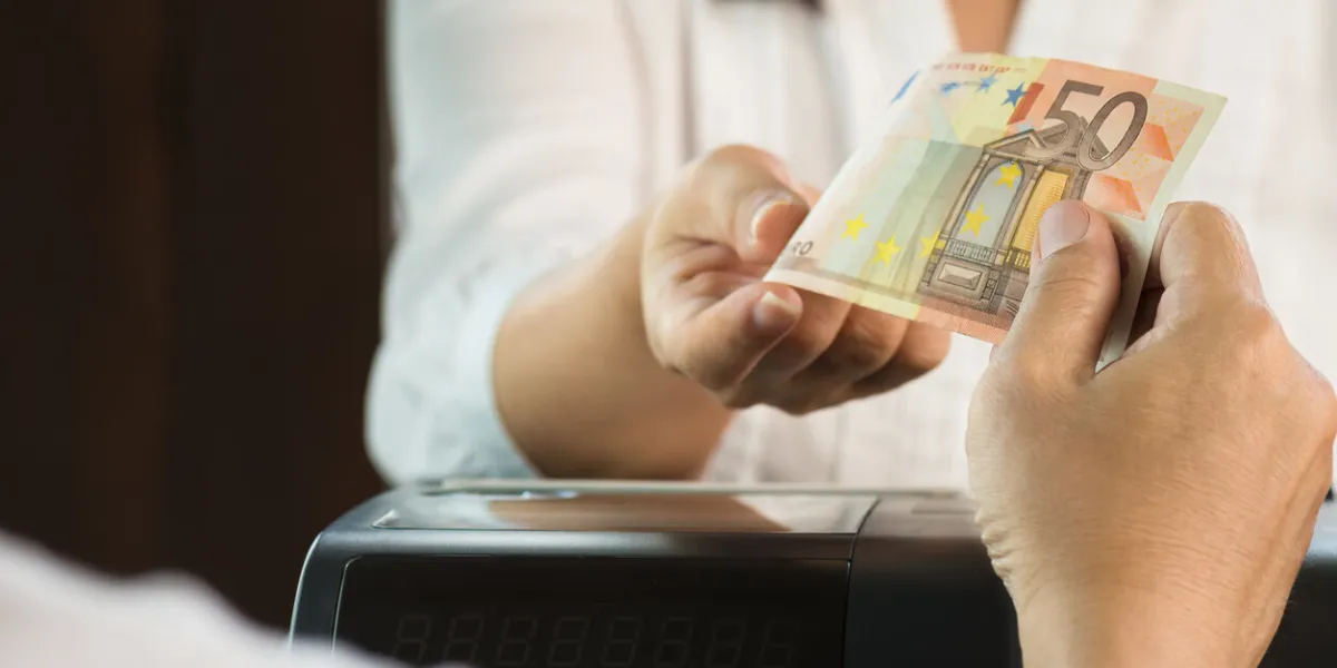 young man paying cash at retail shop customer and woman cashier in white dresses holding euro money
