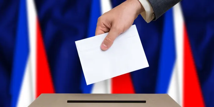 election in france the hand of man putting his vote in the ballot box french flags on background