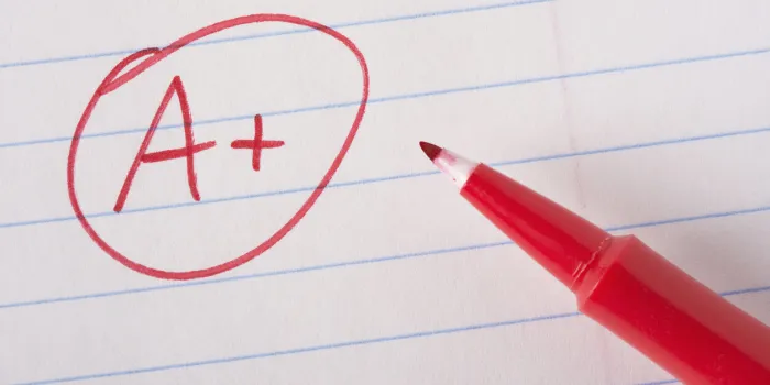 a plus (a+) grade written in red pen on notebook paper with the pen sitting there