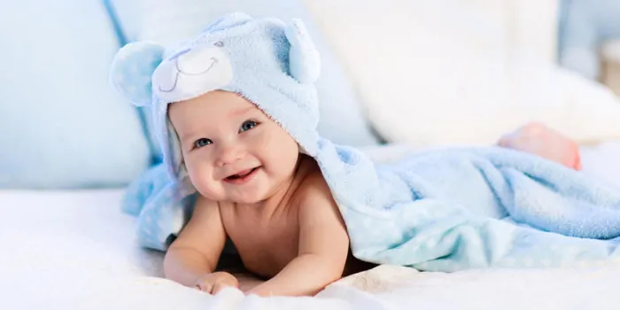 bébé, porter, couche-culotte, et, bleu, serviette, dans, blanc, ensoleillé, chambre nouveau-né, reposer, dans, lit, après, bain, ou, douche, pépinière, pour, enfants, textile, et, literie, pour, enfants nouveau-né, à, jouet, ours