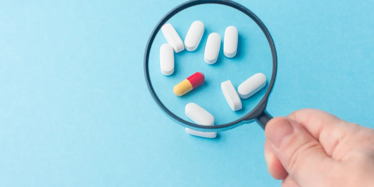 concept - pharmaceutical testing, testing of medicines, magnifying glass, tablets on a blue background doping control