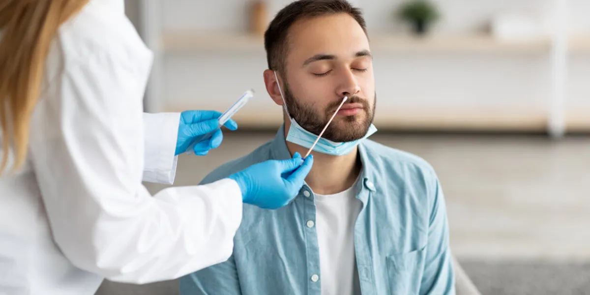 doctor making covid-19 pcr test for male patient at home millennial guy undergoing coronavirus diagnostic procedure indoors viral disease prevention and treatment concept