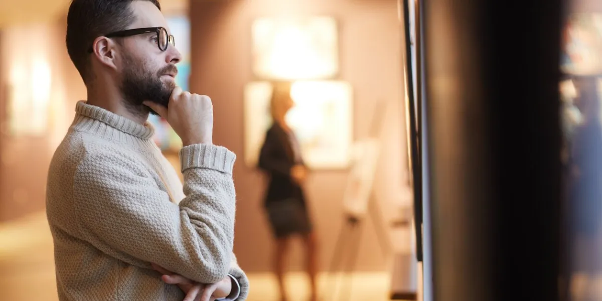 side view portrait of mature bearded man looking at paintings while enjoying exhibition in modern gallery or museum, copy space