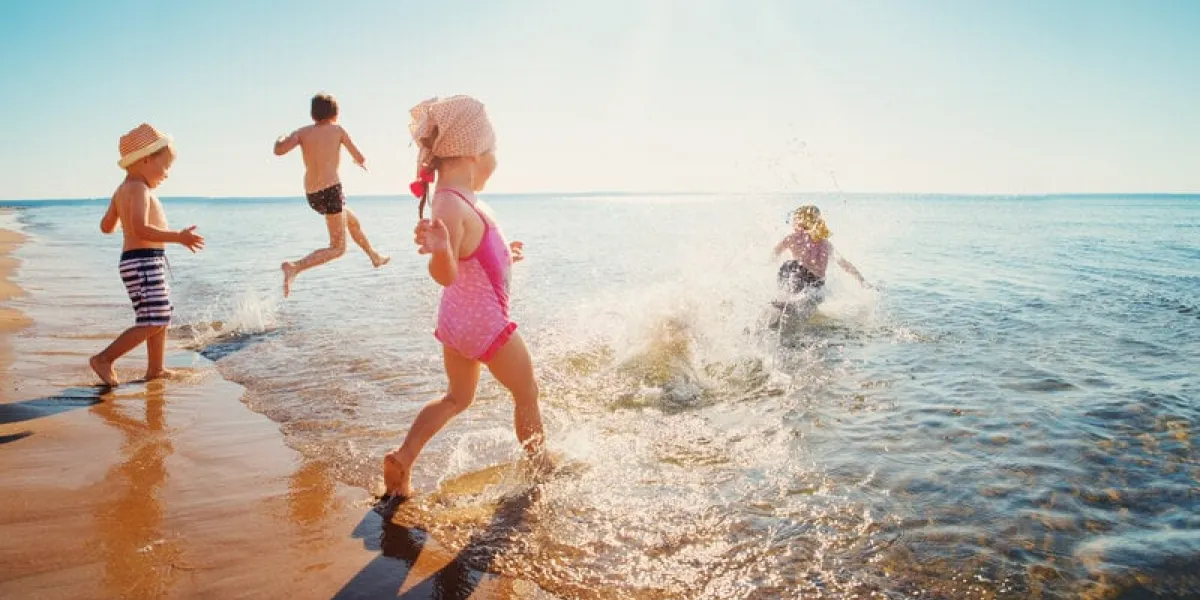 boys and girls playing on the beach on summer holidays children in nature with beautiful sea, sand and blue sky happy kids on vacations at seaside running in the water