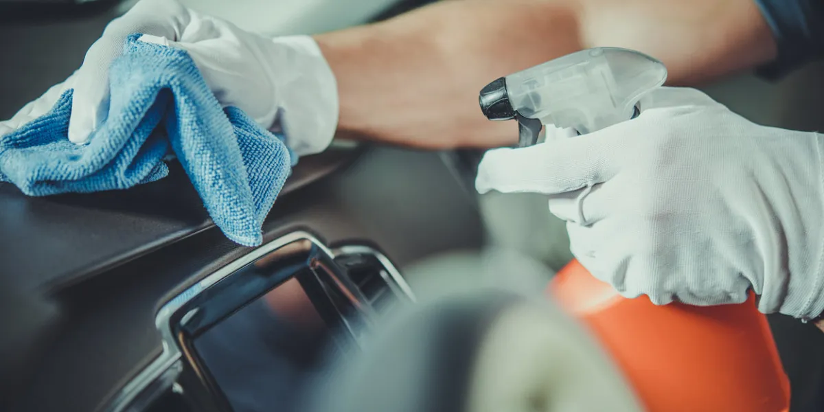worker cleaning car dashboard taking care of vehicle interior automotive services