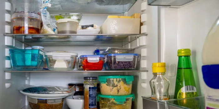 open fridge with food leftovers and meal plan in glass containers domestic refrigerator for healthy eating leftover food, yogurt, cheese and other groceries