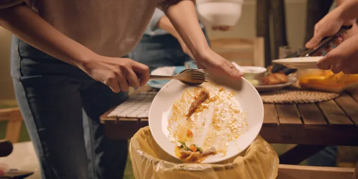 group of people party at home after meal eating throw away leftovers food to plastic bag junk trash bin net zero waste go green eco friendly lifestyle reduce household scrap save the planet earth