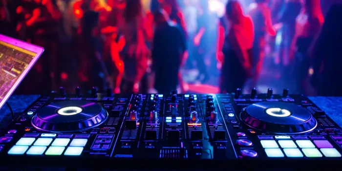 music controller dj mixer in a nightclub at a party against the background of blurred silhouettes of dancing people