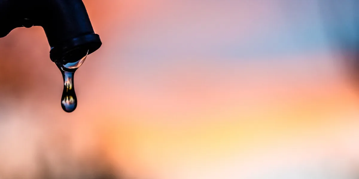 drop of water coming out of a metal tap with a soft background in a park of madrid city