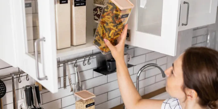 laughing young female housewife posing during general cleaning, tidying up in cupboard kitchen woman placing, sorting food into pp boxes for comfortable storage at cuisine having positive emotion