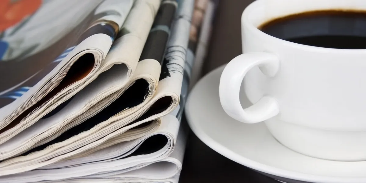 pile of newspapers and cup of coffee on the table