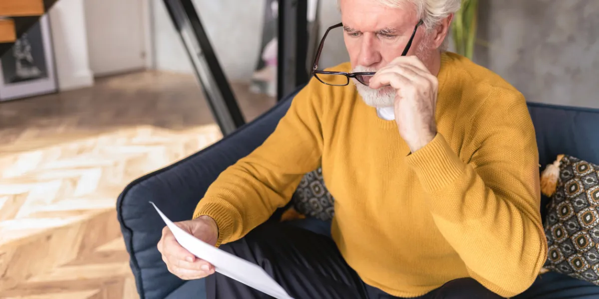 senior man reads document from bank about credit debt financial crisis concept