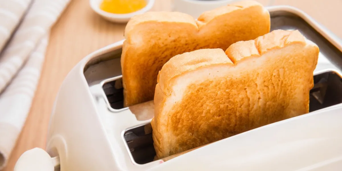 bread slices in toaster with coffee and jam