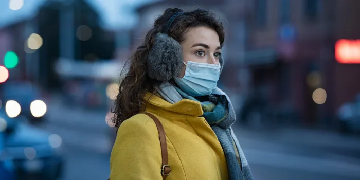 woman wearing medical protective mask outdoor during dusk young woman wearing face mask against pollution standing outdoors on winter evening girl with gray earflap in winter city street during coronavirus outbreak