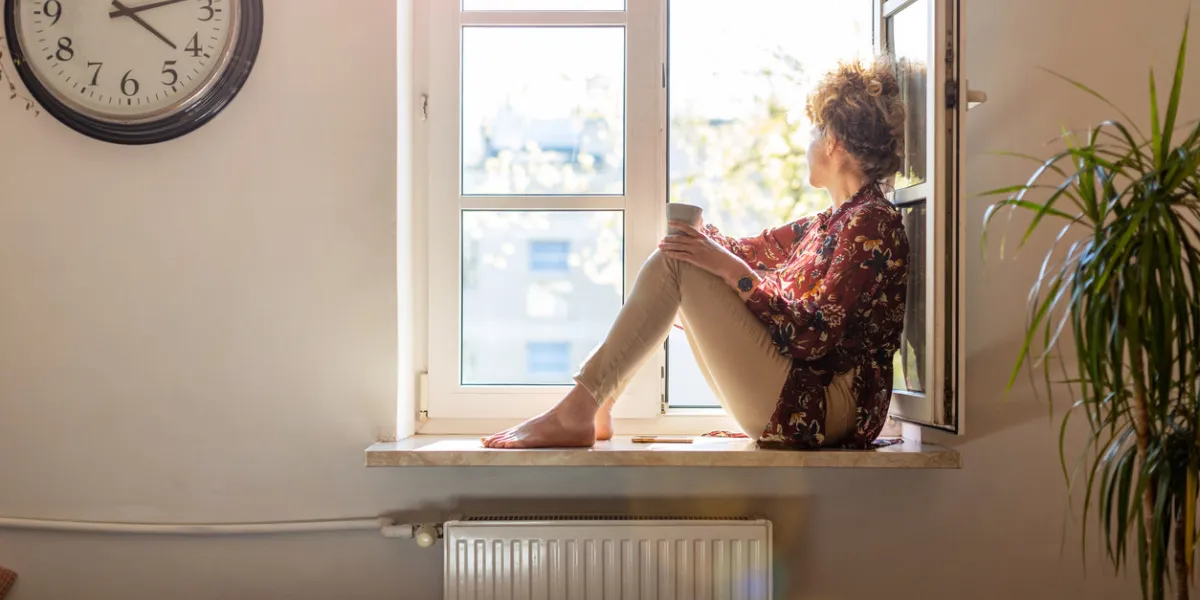 beautiful young woman sitting at a window sill having rest