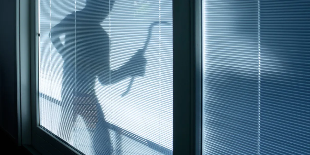 burglar wearing a balaclava looking through the house window