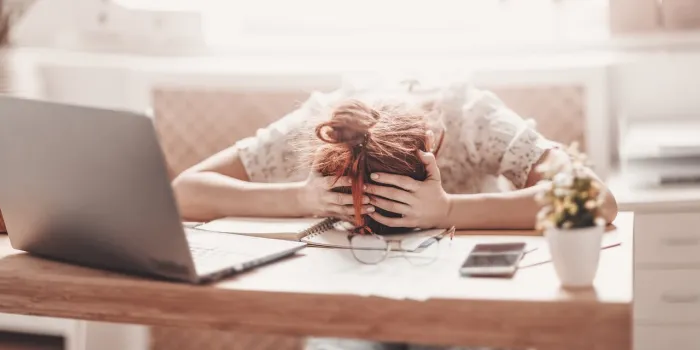 tired woman putting her head on her hands on the desk in the office concept of overworked