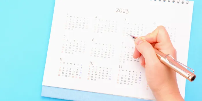 female hands write in calendar 2023 on a blue background, concept of planning