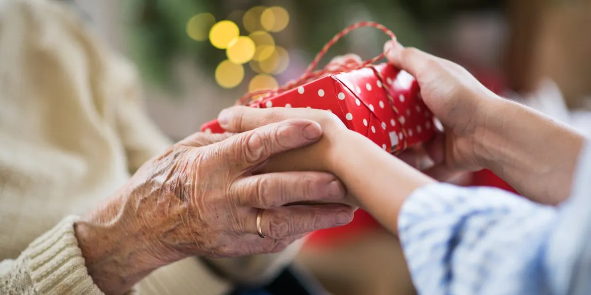 close-up of hands of senior and young woman holding a present at christmas time