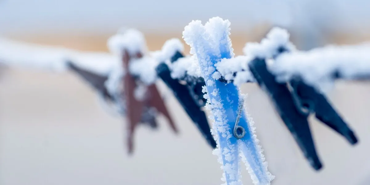 frozen colorful clothes-pins on a rope at winter morning