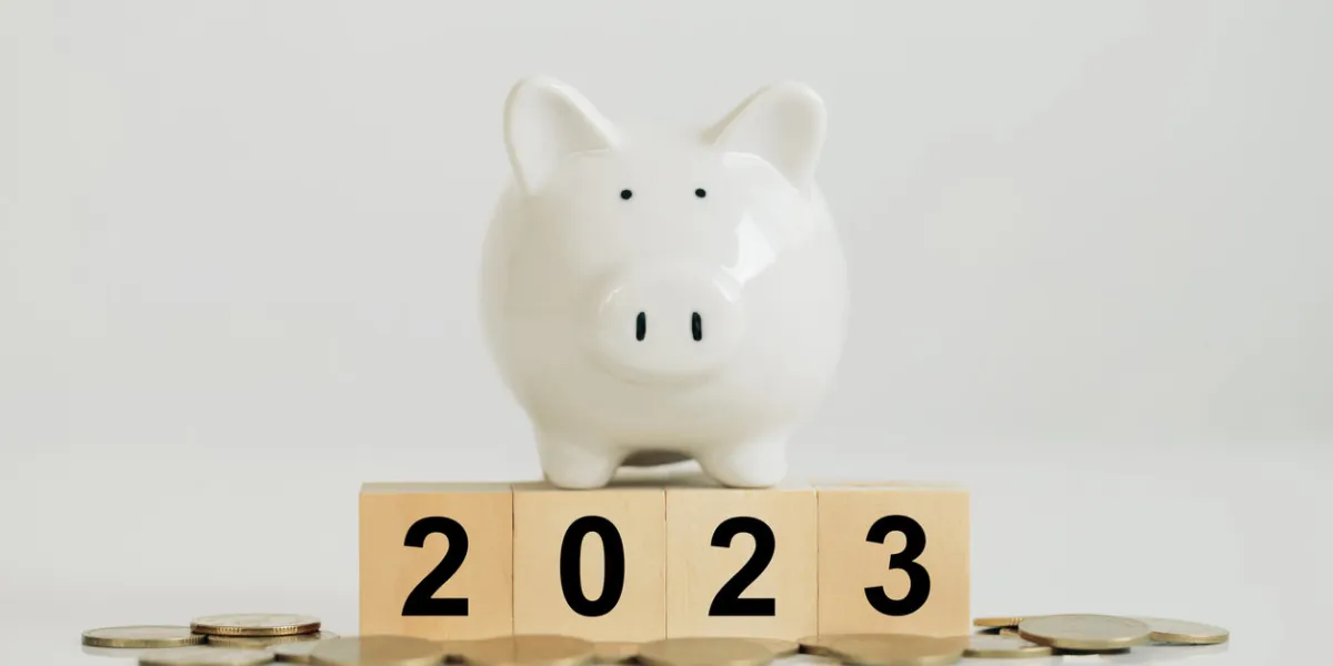 white piggy bank on a wooden block with the numbers 2023 put on coins idea for starting the new year and saving money budget, tax, investment, financial, savings, and new year resolution concepts