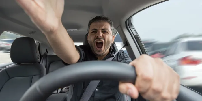 wide angle look inside in the car of actually driving young male with hands in foreground