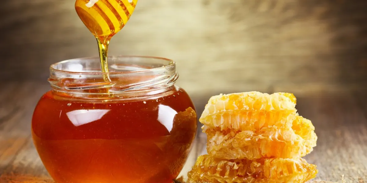 jar of honey with honeycomb on wooden table