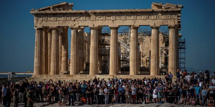 tourists stand in front the parthenon temple atop the acropolis hill during a ceremony marking the anniversary of the liberation of athens from nazi occupation, on october 12, 2019 in athens (photo by angelos tzortzinis   afp)