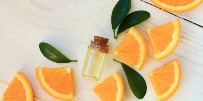 bottle with essential oil, citrus scattered on wooden table