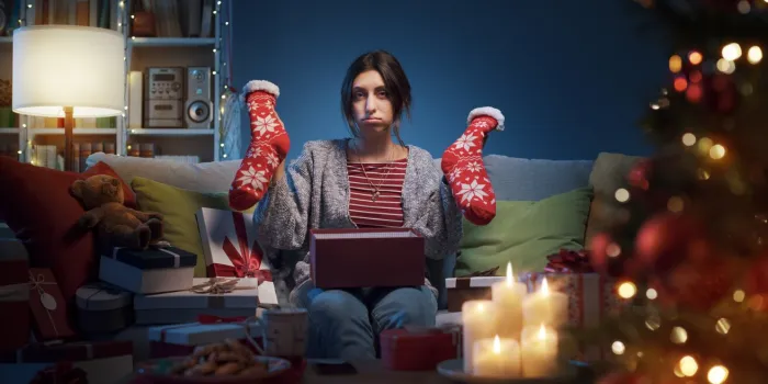 sad disappointed woman opening christmas gifts at home, she received christmas socks