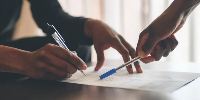 cropped shot of an unrecognizable man filling a document with the help of a financial advisor at home