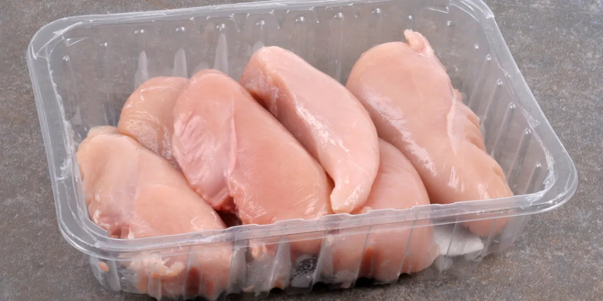 tray of chicken fillets in close-up on a gray background