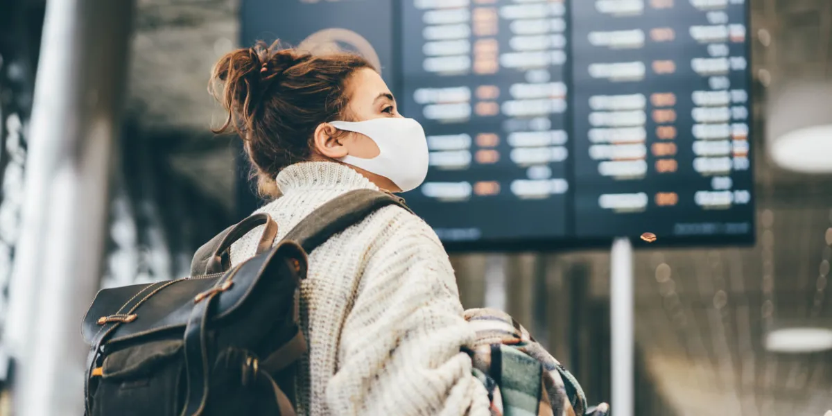 woman in protection mask looking at information in airport