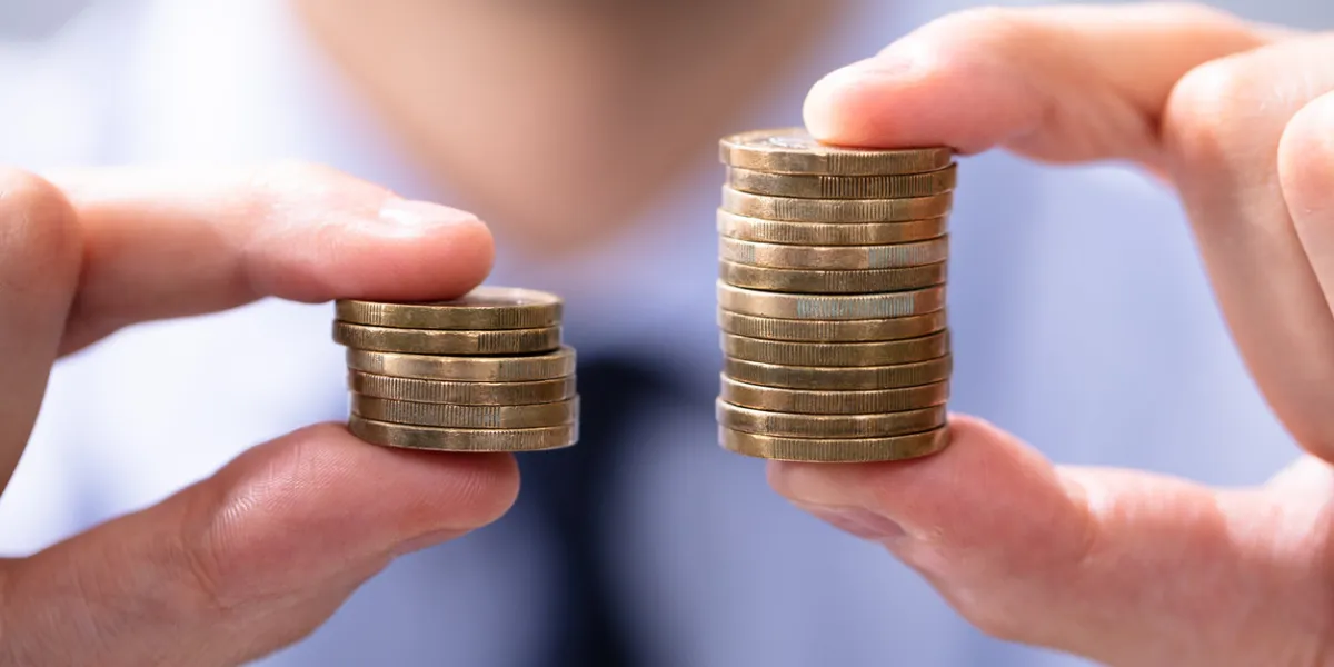 man holding two coin stacks to compare