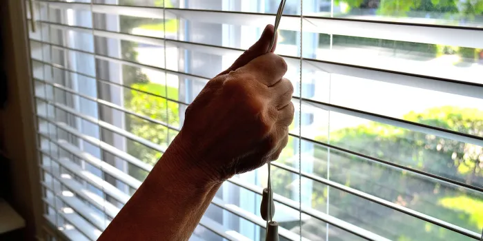 lifestylethis close up shot, shows an arm lowering or opening a bedroom window shade